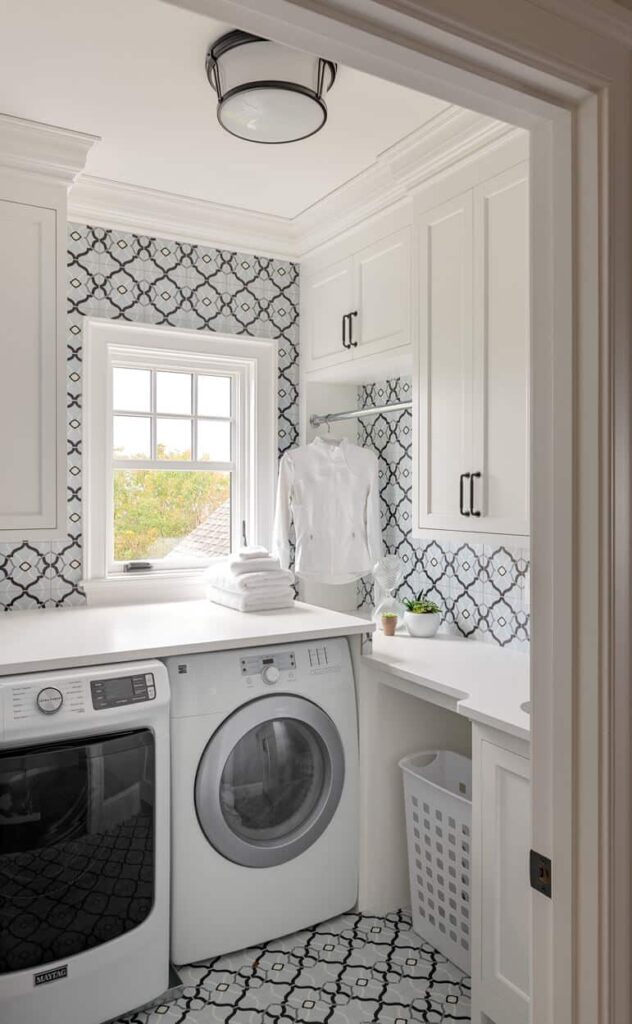 A modern laundry room featuring a bold black and white geometric-patterned tile on both the floor and the backsplash for a cohesive look.