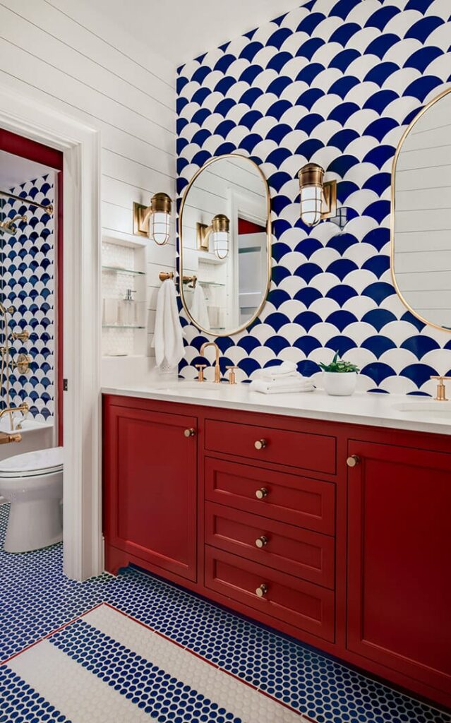 A bold, nautical-themed bathroom with a floor of blue penny tiles, featuring a custom-designed rug inlay made from red, white, and blue penny tiles in a striped pattern.